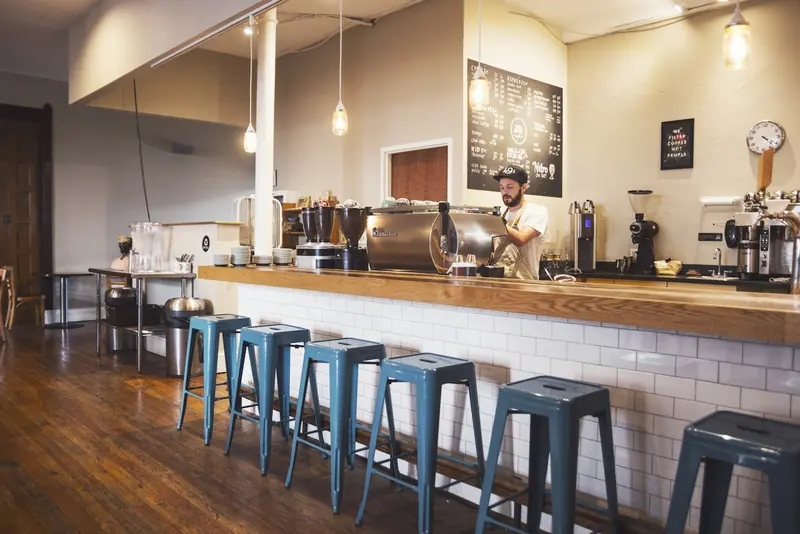 The café’s counter with stools, pendant lights and a chalkboard menu.