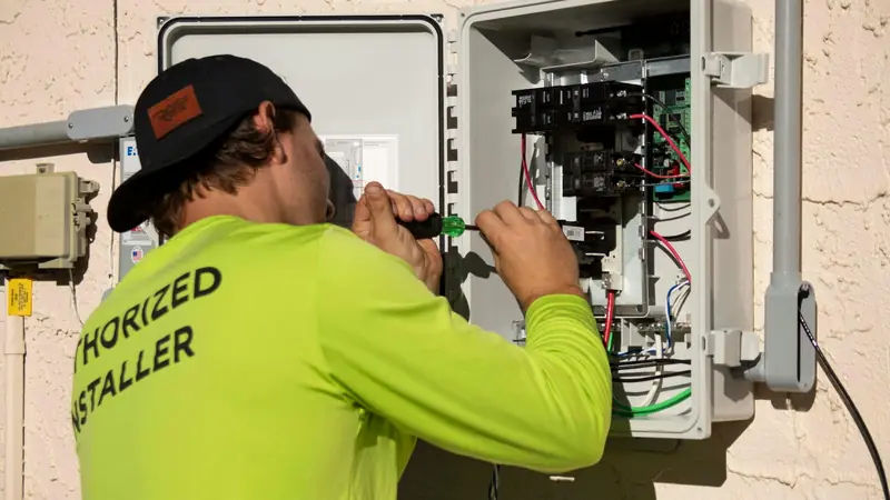 An electrician in hi-vis working on an outdoor switchboard.