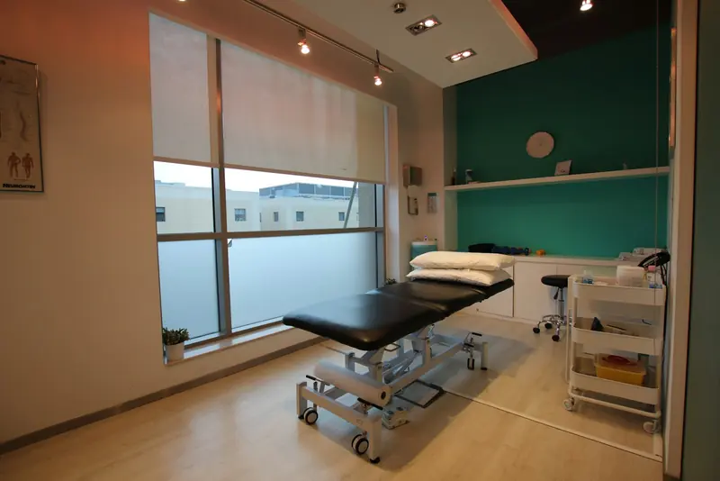 A treatment room with a padded table and a window onto the street.