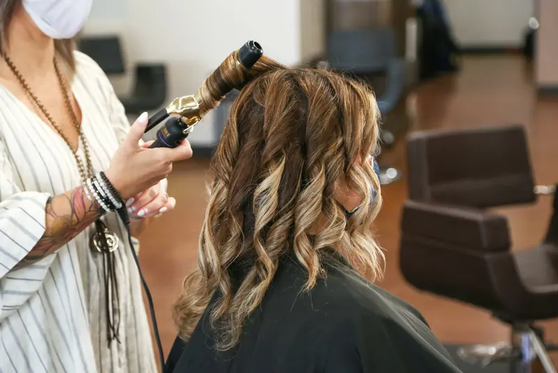 A stylist curling a client’s hair.
