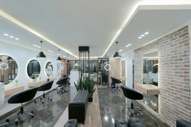 An empty salon with black chairs, round mirrors and a brick wall.